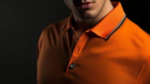 Um homem com uma camisa pólo laranja posando contra um fundo preto em uma loja de roupas.