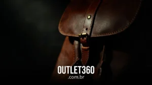 Close-up de uma bolsa de couro marrom com detalhes de fivela, em um fundo escuro. O texto "OUTLET360.com.br" aparece na parte inferior da imagem.