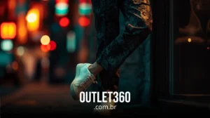 Pessoa usando calça estampada e tênis branco em uma rua da cidade à noite; luzes borradas ao fundo. O texto diz: OUTLET360.com.br.