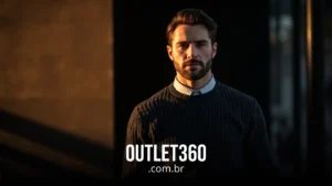 Um homem com barba e suéter escuro está sob luz solar parcial com o texto "OUTLET360.com.br" exibido na parte inferior.