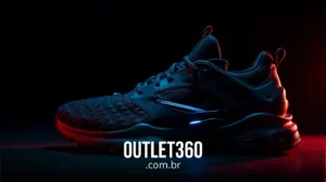 Tênis esportivo preto exibido em um fundo escuro com iluminação vermelha e azul; o texto "OUTLET360.com.br" está visível na parte inferior.
